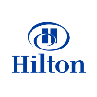 A modern Hilton hotel exterior with large glass windows and a welcoming entrance, showcasing contemporary architecture.