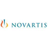 A professional team meeting at Novartis, discussing strategies with documents and laptops on the table.